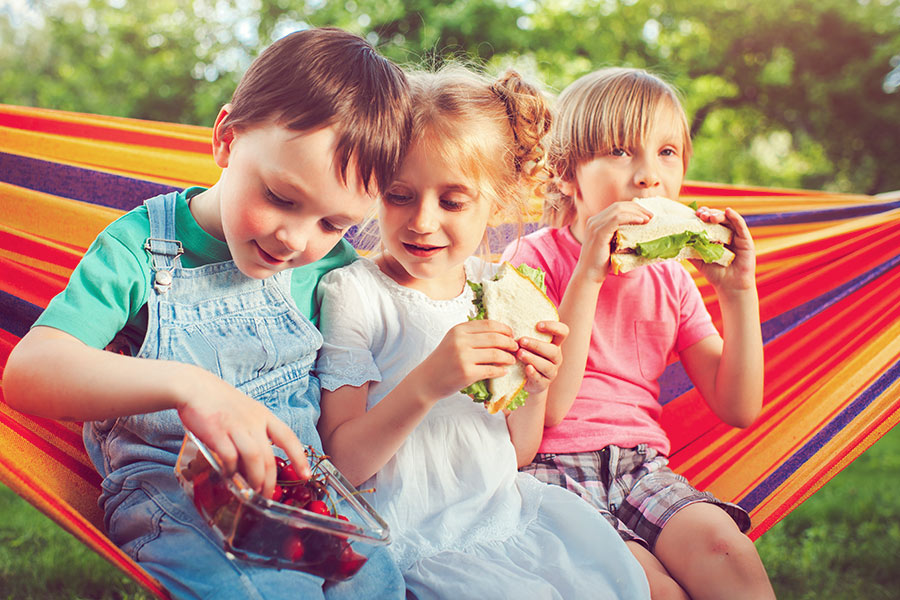 Children Eating a Summer Lunch While Sitting on a Hammock