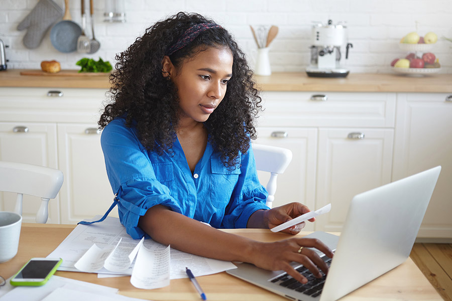 Woman reviewing receipts with her phone and laptop.