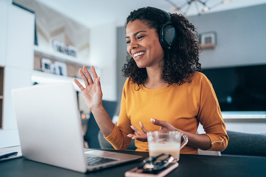 Smiling Woman Waving in Headphone on Her Laptop